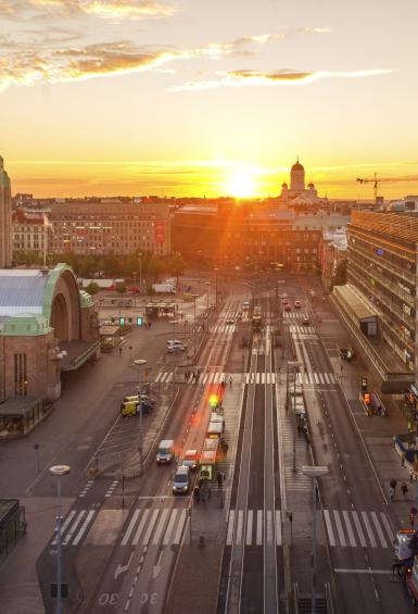 Taken from a height and looking down Kaivokatu towards the Helsinki Cathedral in the distance, the sun rises over a still quiet Helsinki, the Helsinki Central Railway Station standing on the left side of the photo.