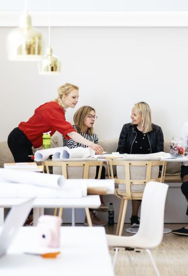 A team of five are having a meeting around a large table in a group space offered by OP Vallila