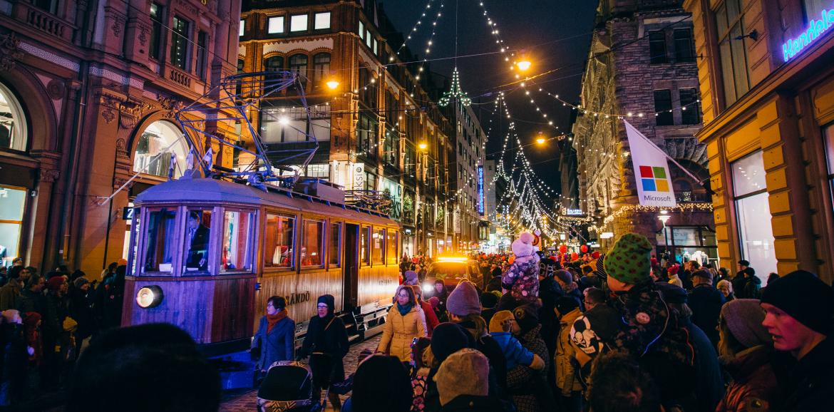 Opening of Aleksanterinkatu at Christmas, where large crowds gather in the street to see the Christmas lights as an old tram is passing by. 