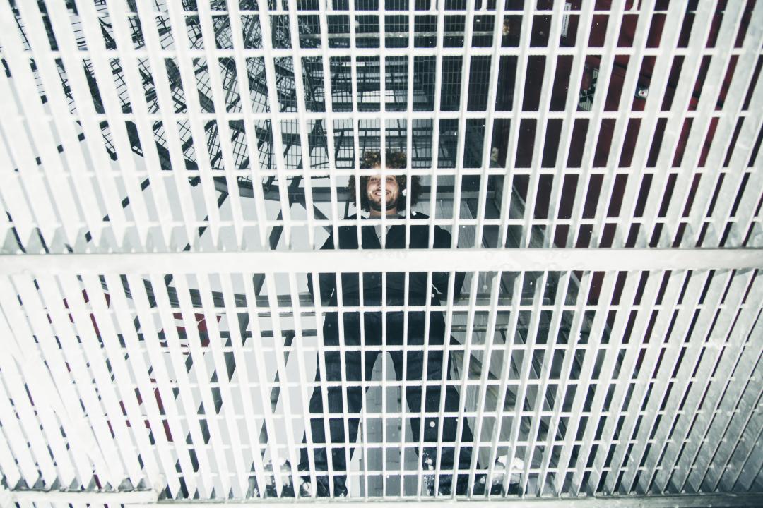 Viewed from below, founder of Neverthink, Aviv Junno, standing on a metal grid floor, looking down at the camera.
