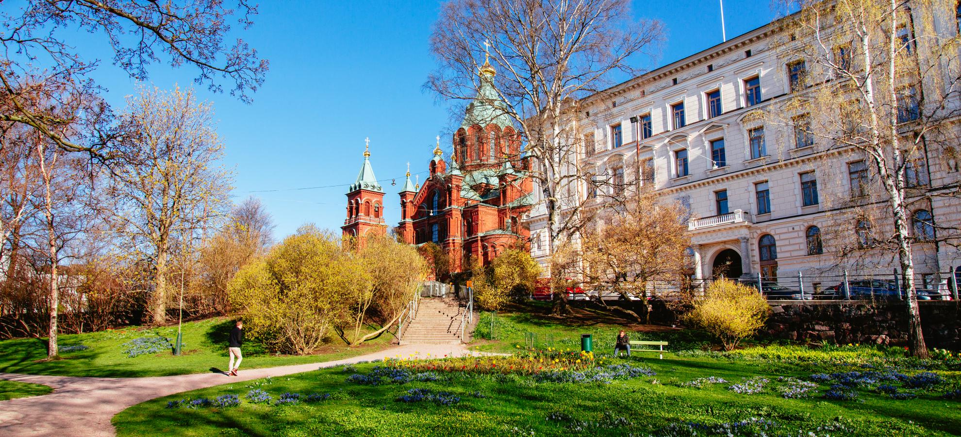 A view from Tove Jansson park looking towards the Uspenski Cathedral, art nouveau style apartments on the right. It's a clear day with a blue sky in autumn.  