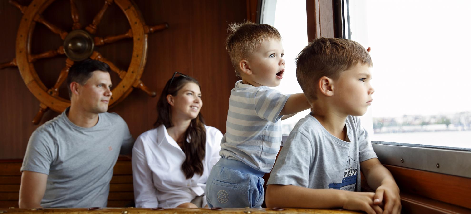 Family with two little boys sitting on Suomenlinna ferry, looking thru window