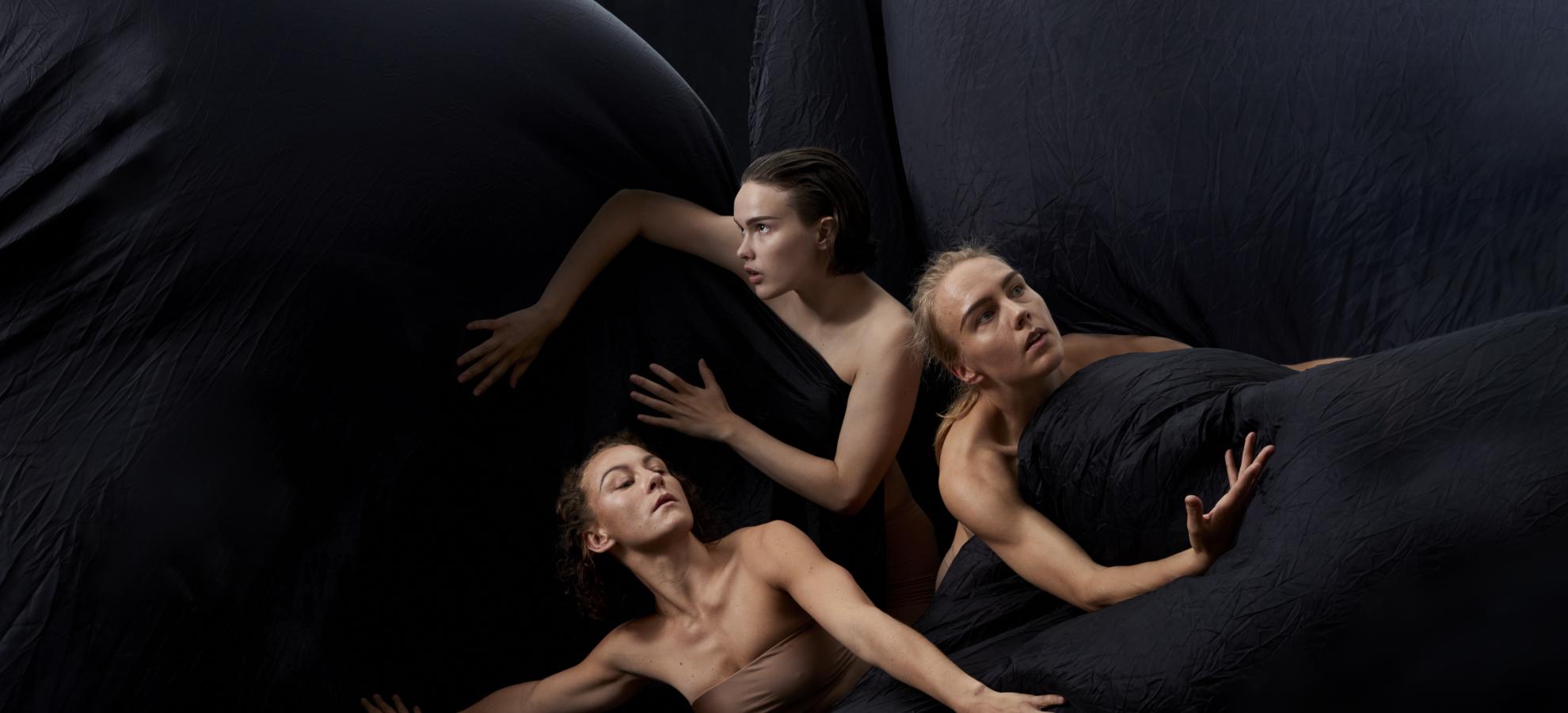 A press image of Tero Saarinen Company's piece HZ, presenting three women in middle of fabric